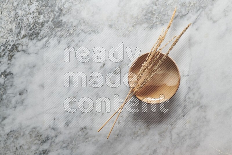 Wheat stalks on multicolored pottery plate on grey marble background