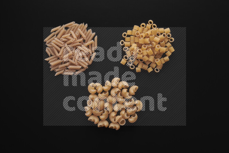 Different pasta types in bunches on black background
