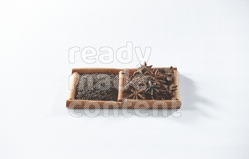 مربعان من أعواد القرفة ممتلئان بالشاي الأسود واليانسون النجمي علي خلفية بيضاء