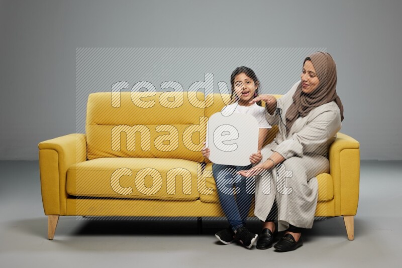 Mom and daughter sitting holding social media sign on gray background