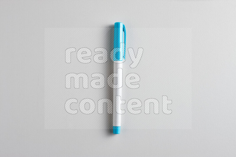 A close-up showing a single coloring pen with a cap on grey background