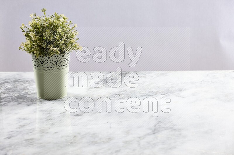 Artificial plant in green decorative pot on grey marble background