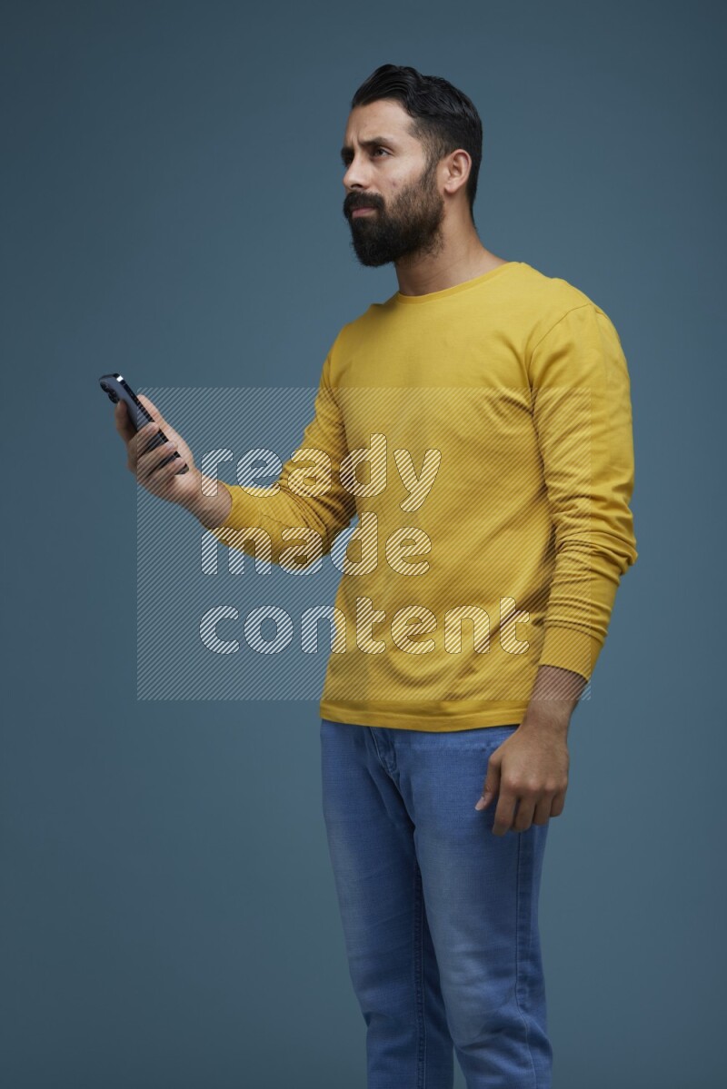Man typing on his phone in a blue background wearing a yellow shirt