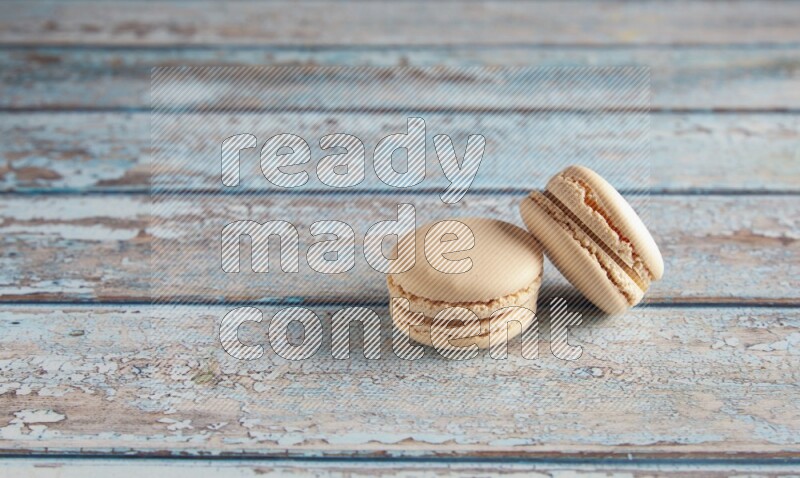 45º Shot of two White Caramel fleur de sel macarons on a light blue wooden background