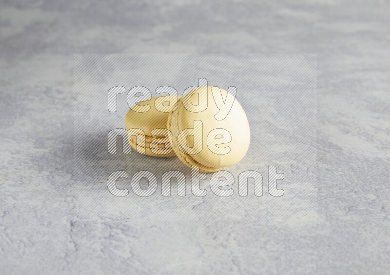 45º Shot of two Yellow Vanilla macarons  on white  marble background