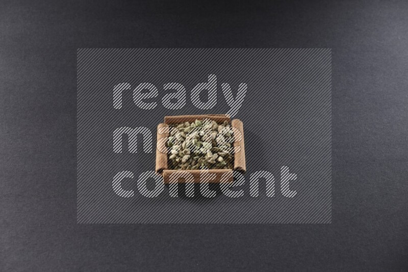 A single square of cinnamon sticks full of Cardamom on black flooring