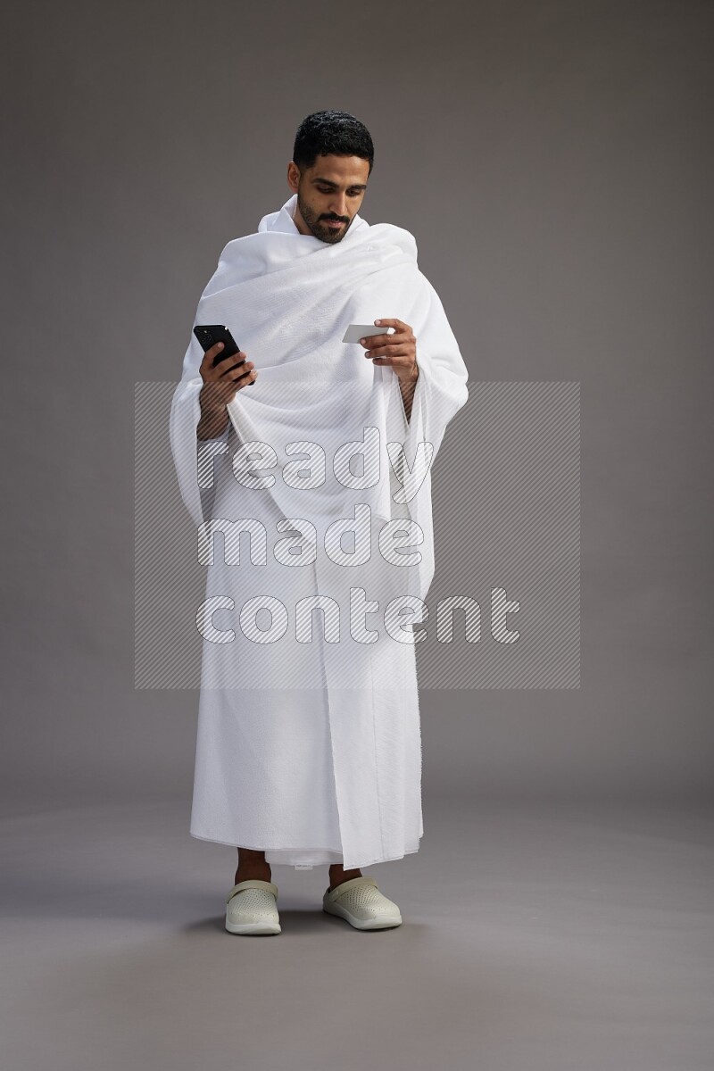 A man wearing Ehram Standing holding ATM card on gray background