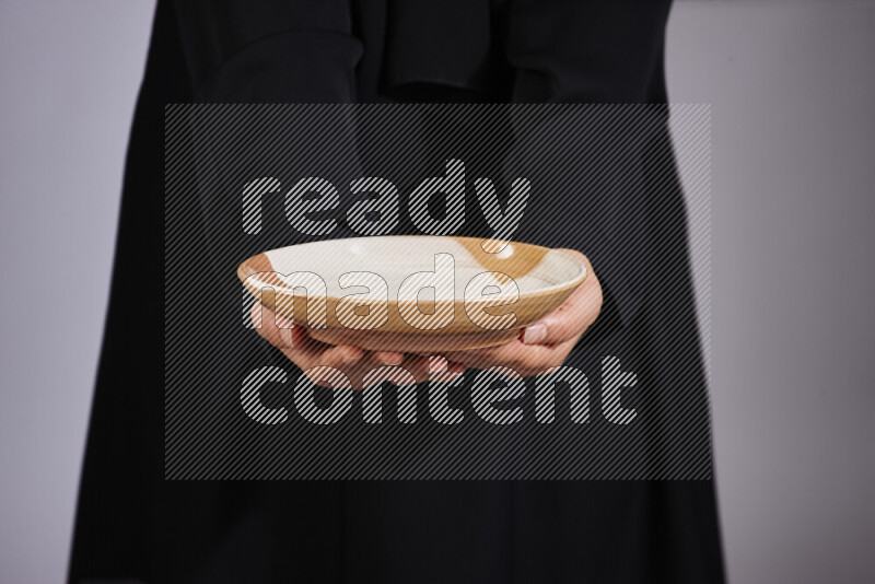 A woman in black abaya holding different pottery essentials in different positions
