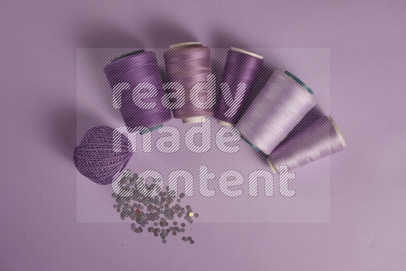 A purple collection of sewing and tailoring tools arranged on a purple background