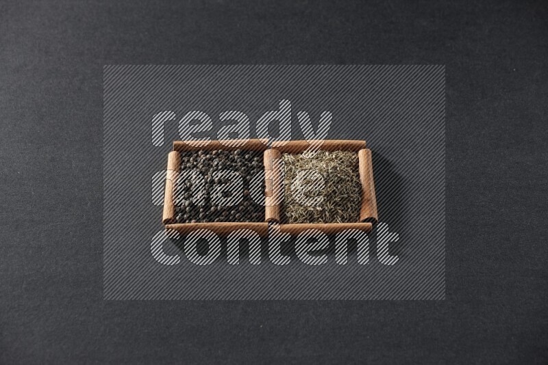 2 squares of cinnamon sticks full of black peppers and cumin on black flooring