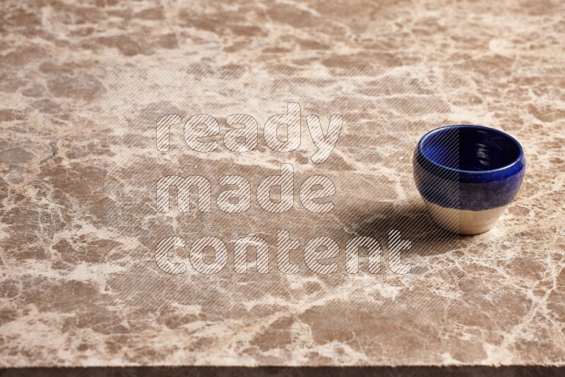 A multicolored pottery cup on beige marble background