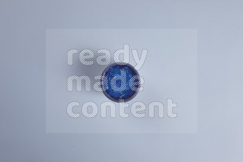 Multicolored pottery bowls full of colored buttons on blue background