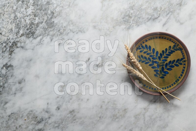Wheat stalks on decorative pottery plate on grey marble background