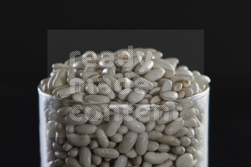 White beans in a glass jar on black background