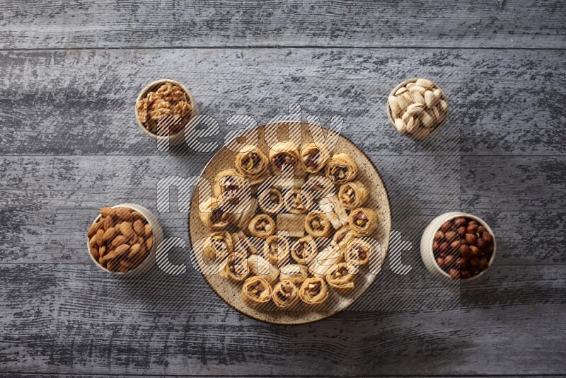 Oriental sweets in a pottery plate with nuts, coffee and honey in a dark setup