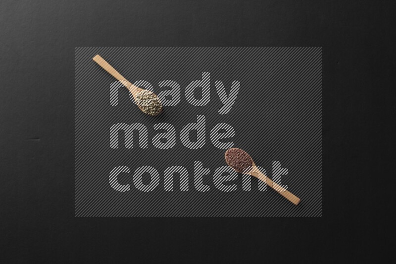 wooden spoons filled with white peppers, mustard seeds, black seeds, garden cress, cumin and flax on black flooring