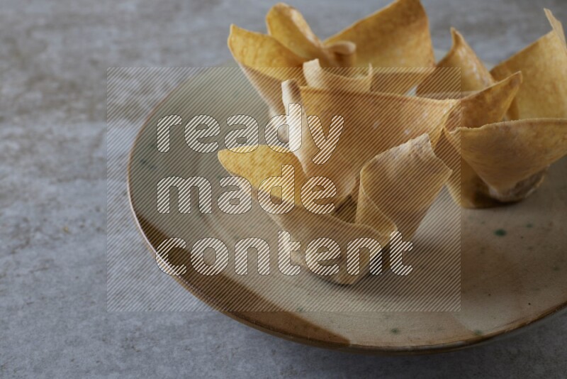 wonton cups with soy sauce ramkin on multi colored pottery on grey textured counter top