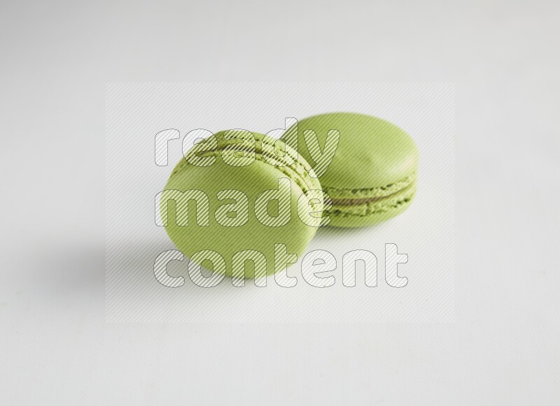 45º Shot of two Green Pistachio macarons on white background