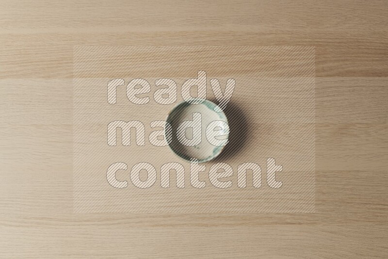 A multicolored pottery bowl on light wooden background