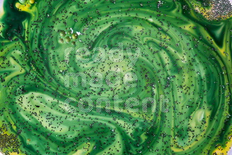 A close-up of sparkling green glitter scattered on swirling yellow and green background