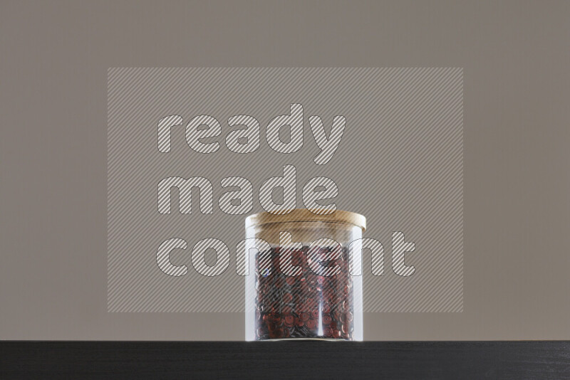 Sequins in a glass jar on black background