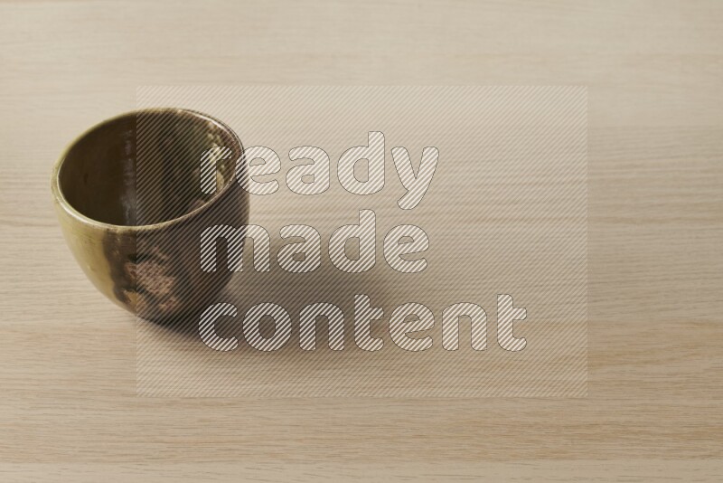 A multicolored pottery cup on light wooden background
