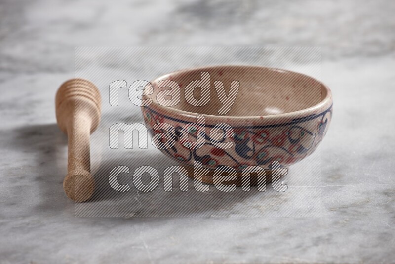 Decorative pottery bowl with wooden honey dipper on the side on grey marble background