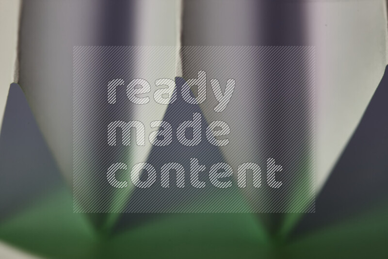 صورة مجردة مقربة تظهر طيات ورقية هندسية حادة بتدرجات اللون الأبيض و الأخضر