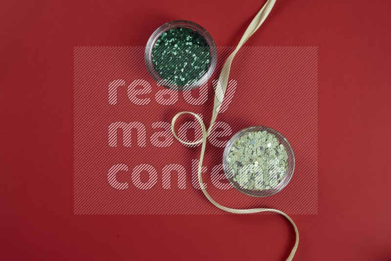 مجموعة من أدوات الخياطة والتفصيل خضراء وحمراء اللون على خلفية حمراء