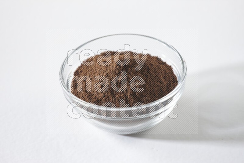 وعاء زجاجي ممتلئ ببودرة القرنفل على أرضية بيضاء