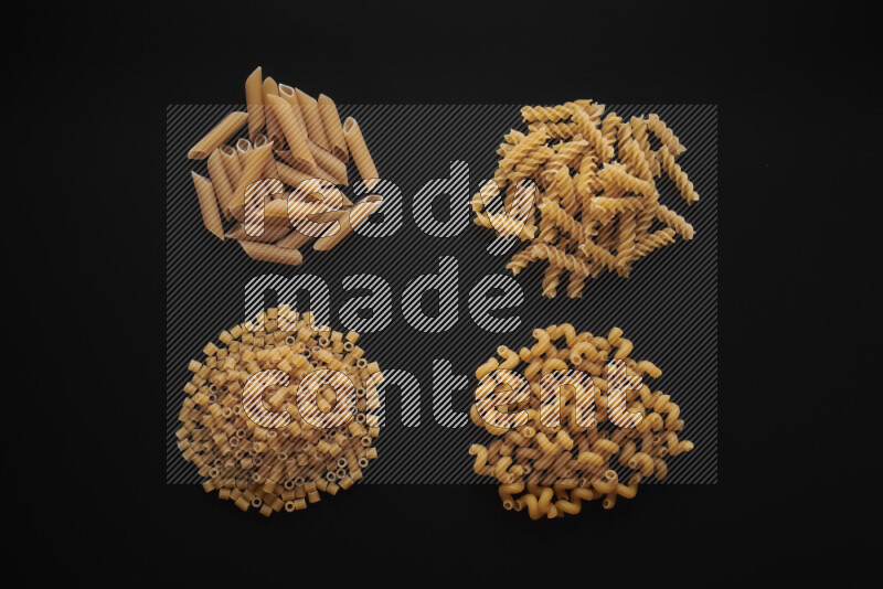 Different pasta types in bunches on black background