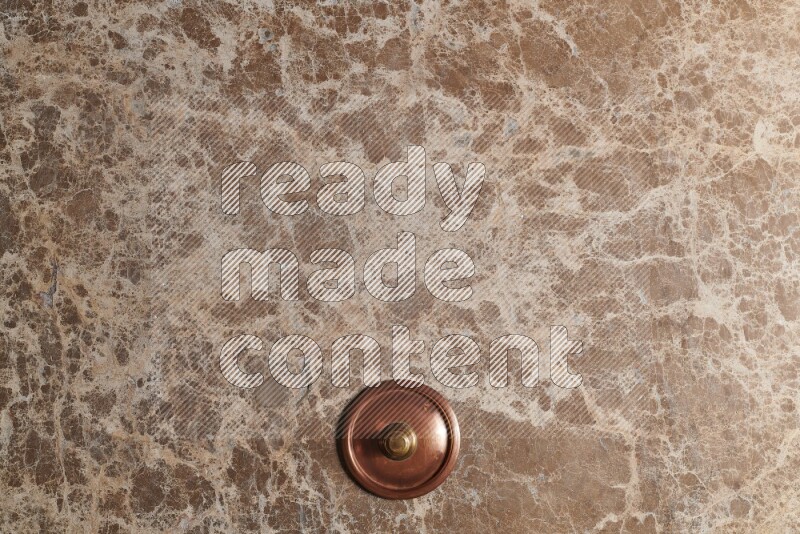 A small copper pot on beige marble background