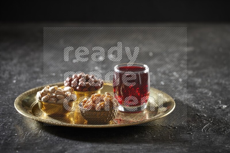 Nuts in metal bowls with Hibiscus on a tray in dark setup