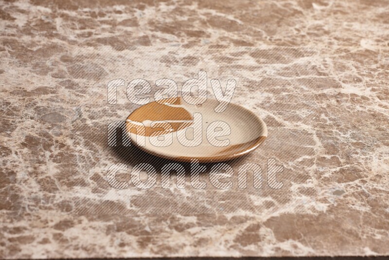 A multicolored pottery plate on beige marble background