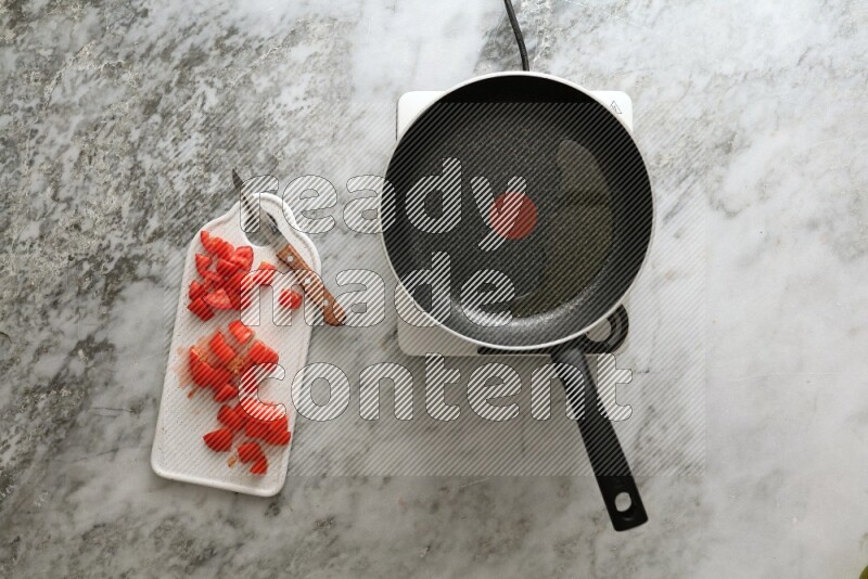 Frying pan on single electric stove on grey marble background