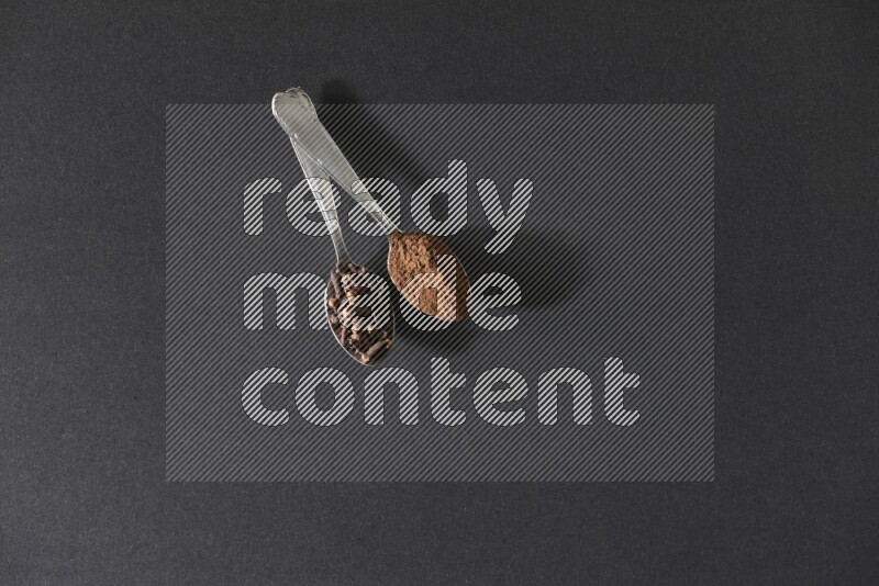 ملعقتان معدنيتان، إحداهما ممتلئة بحبوب القرنفل والأخرى ببودرة القرنفل، على خلفية سوداء