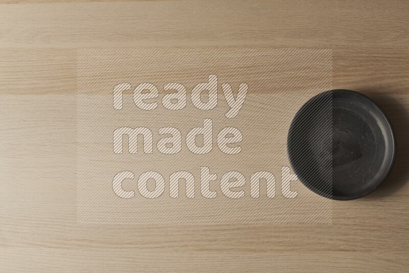 A black pottery oven bowl on light wooden background