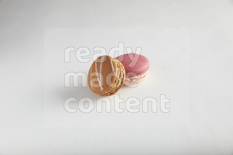 45º Shot of of two assorted Brown Irish Cream, and Pink Litchi Raspberry macarons on white background