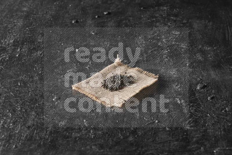 Black pepper on burlap fabric on a textured black flooring