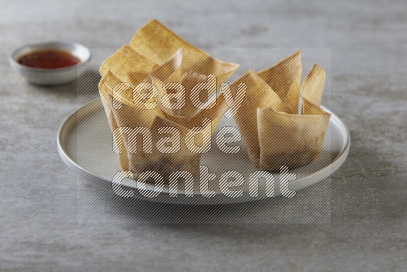 wonton cups with soy sauce ramkin on grey ceramic plate on grey textured counter top