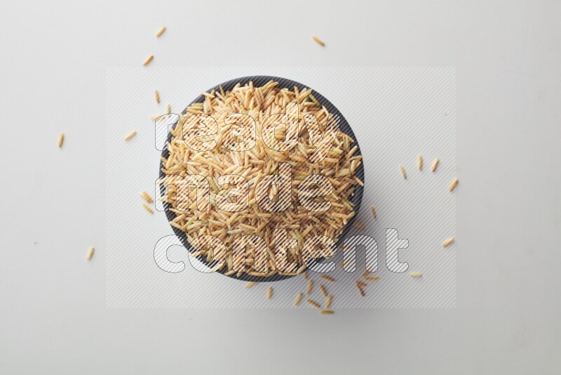 Top-view shot of long grain brown rice in a container on white background