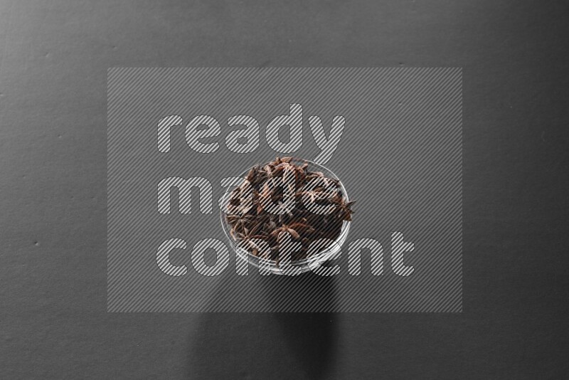 A glass bowl full of star anise on black flooring