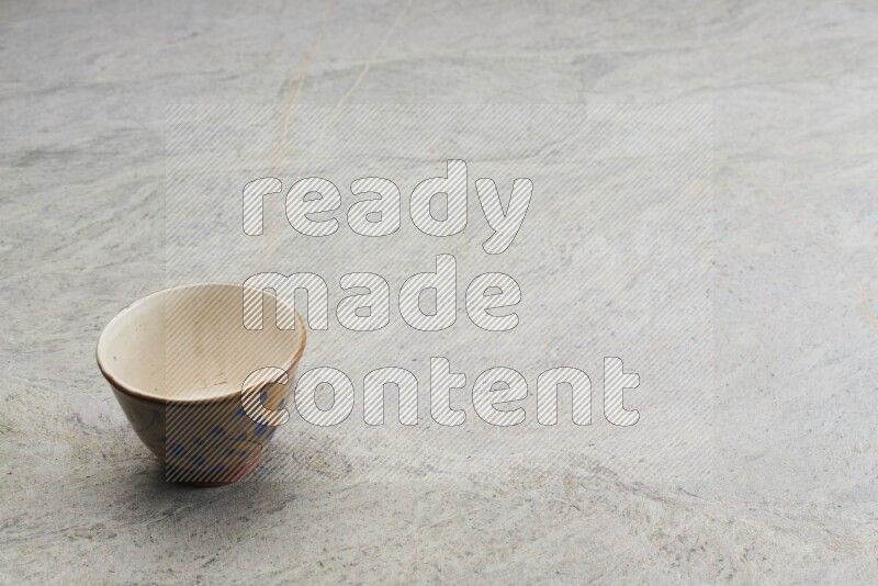 A multicolored pottery bowl on grey marble background