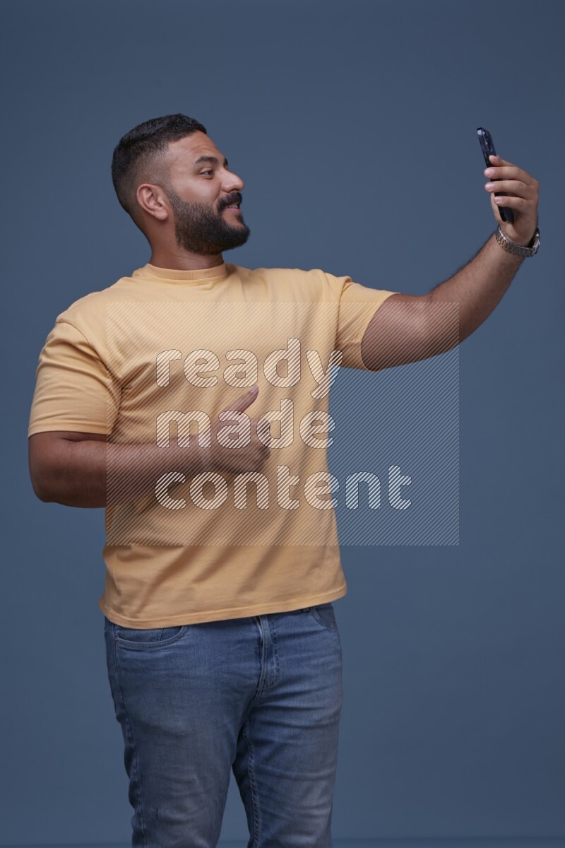 A man Taking A Selfie on Blue Background wearing Orange T-shirt