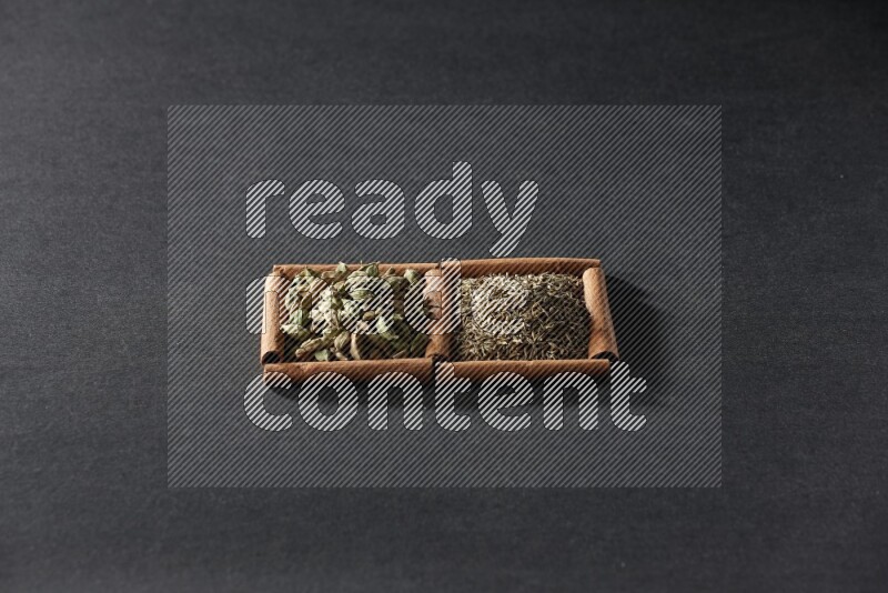 2 squares of cinnamon sticks full of cumin and cardamom on black flooring