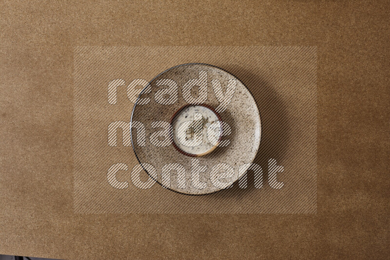 Assorted snacks on a pottery plate with a dipping on brown background