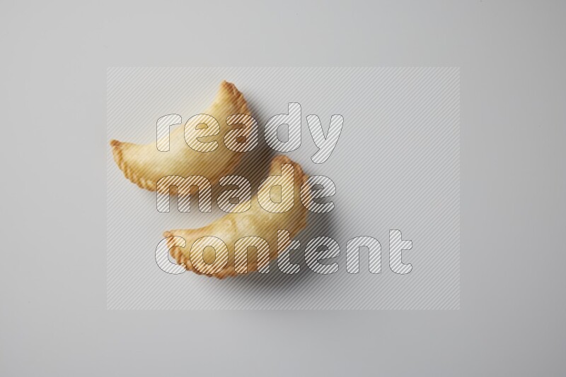 Two fried sambosa from a top angle on a white background