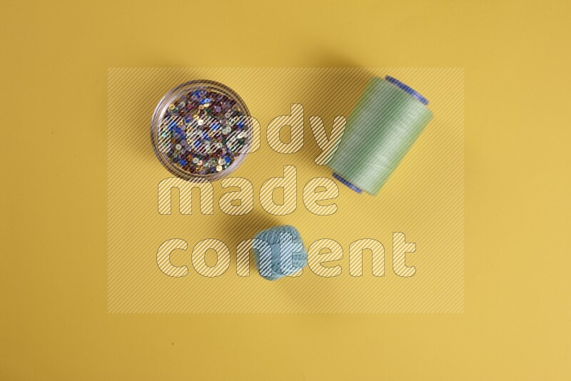 A green collection of sewing and tailoring tools arranged on a yellow background