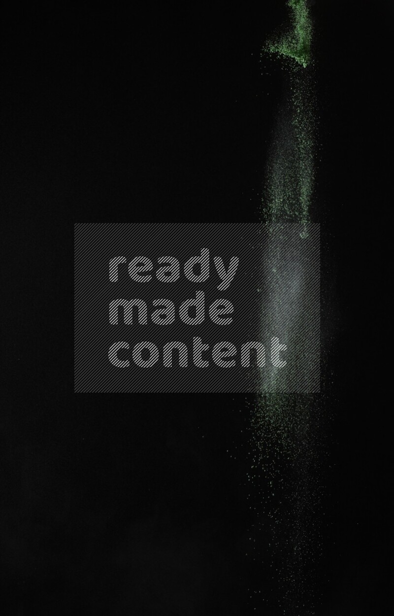 A side view of green powder explosion on black background