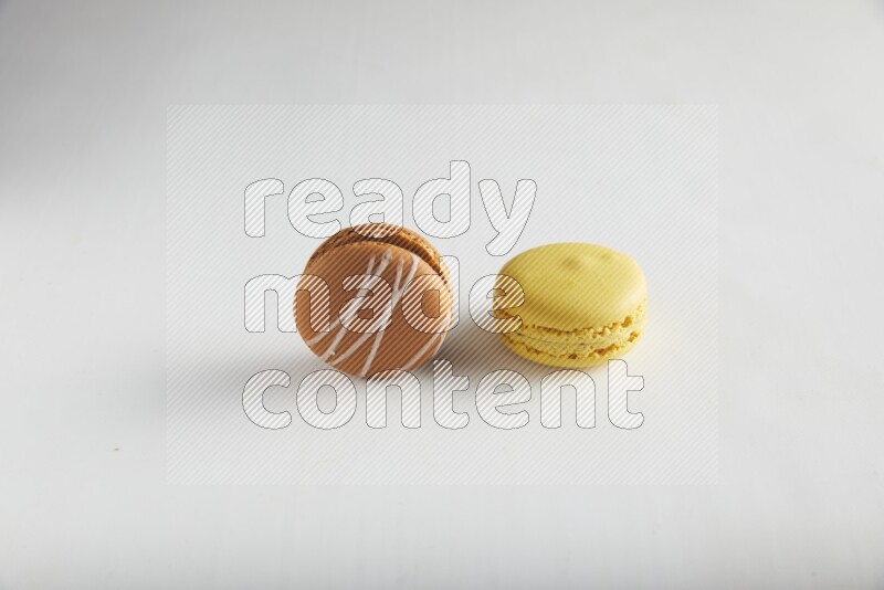 45º Shot of of two assorted Brown Irish Cream, and Yellow Lemon macarons on white background